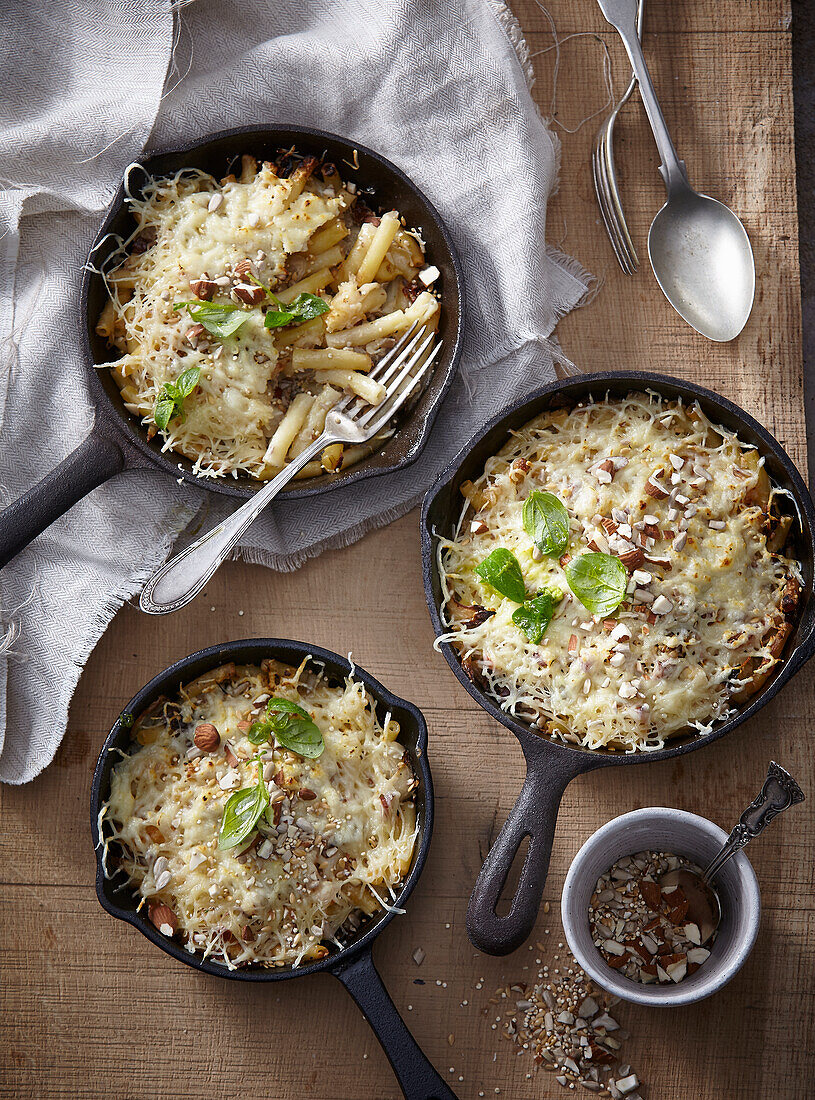 Baked pasta with cheese and chopped nuts in cast iron skillets