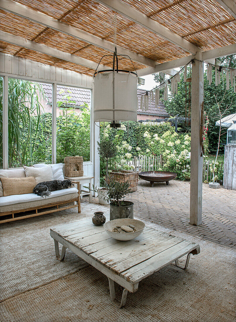 Covered terrace with wooden table and outdoor sofa