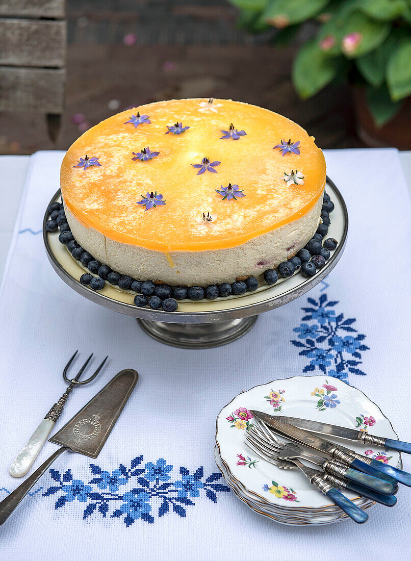 Cheesecake with blueberries and edible flowers on an embroidered tablecloth