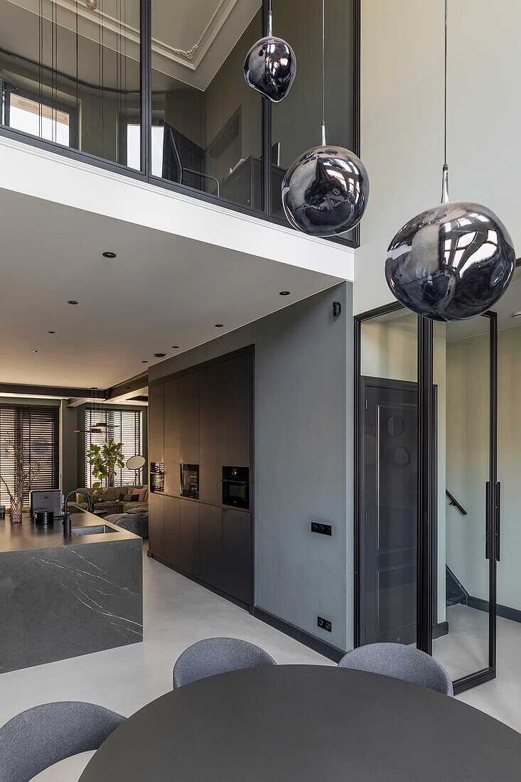 Modern open-plan kitchen with black built in cupboards and view of gallery