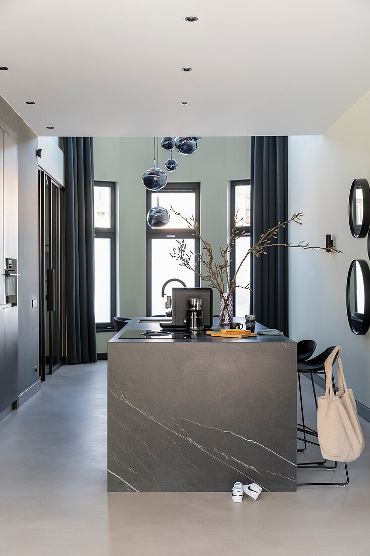 Open-plan kitchen with dark marble island and black curtains