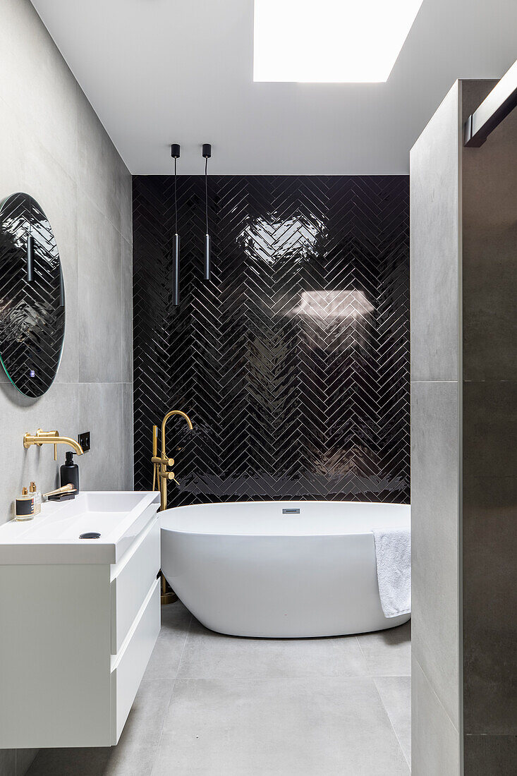 Modern bathroom with free-standing bathtub and black herringbone tiled walls