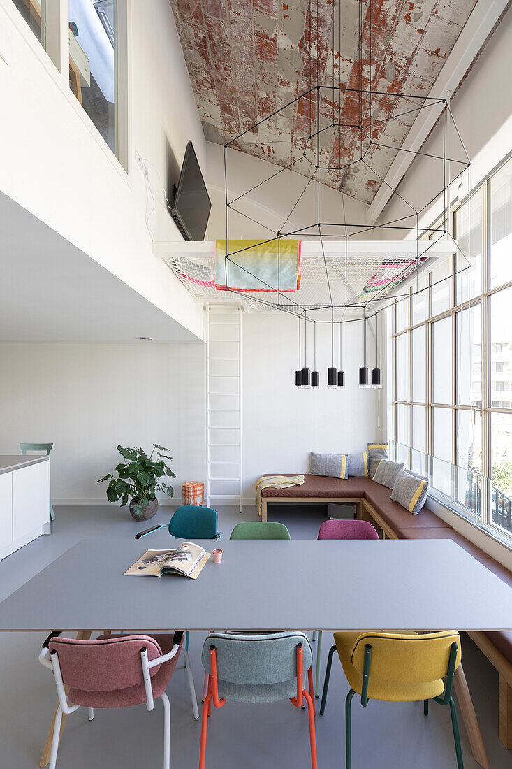 Dining room with colorful seating and modern lighting installation under a rustic ceiling