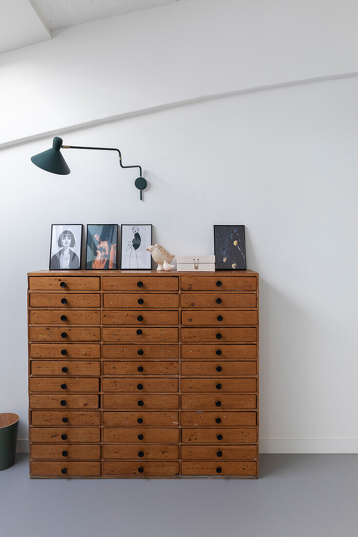 Chest of drawers with wall lamp and framed photos