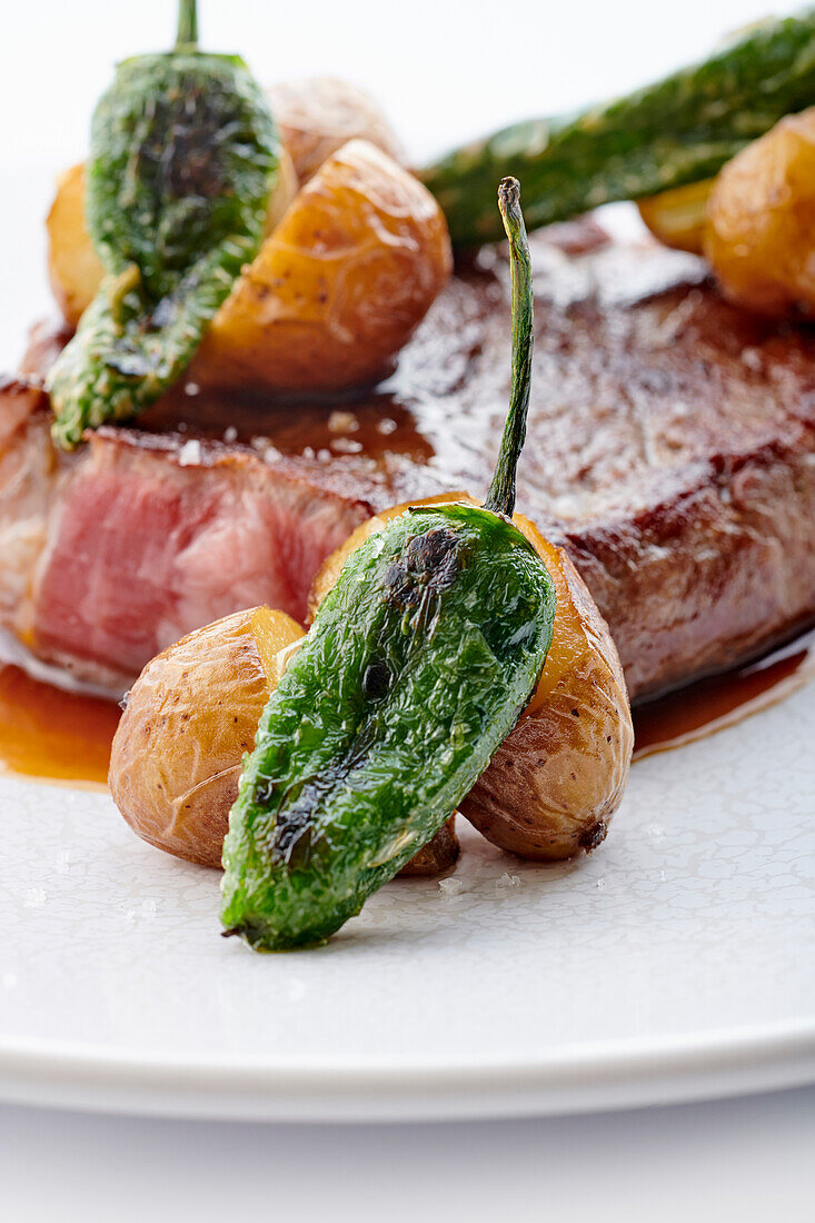 Beef steak with roast peppers, small jacket potatoes and demi-glace