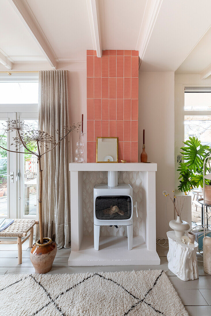 White wood-burning stove, pink tiled wall in the living room