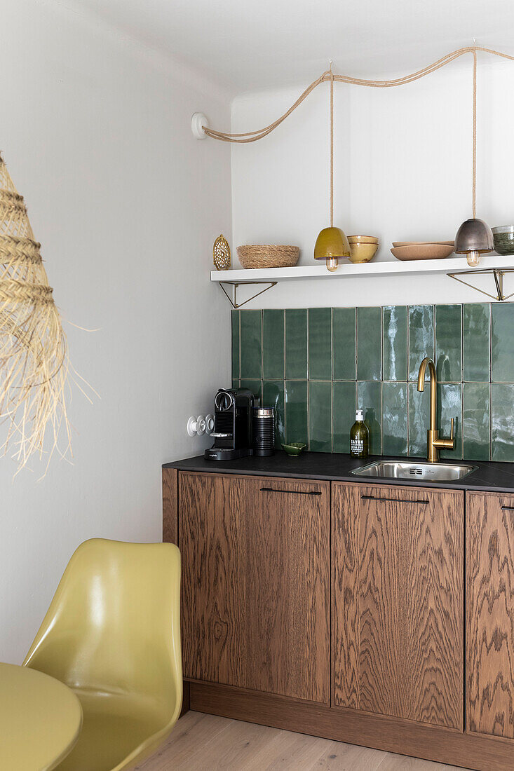 Kitchen with green tiles, wooden cupboards and olive-colored chair