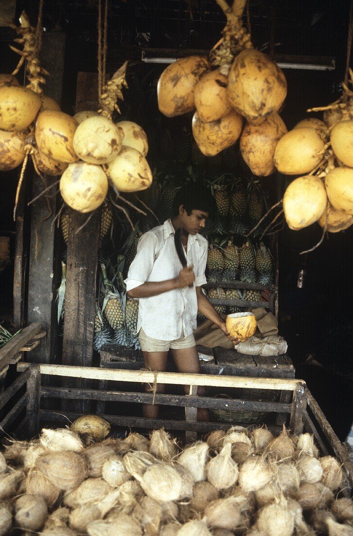 Junger Verkäufer mit Kokosnuss am Kokosnuss-Stand in Thailand