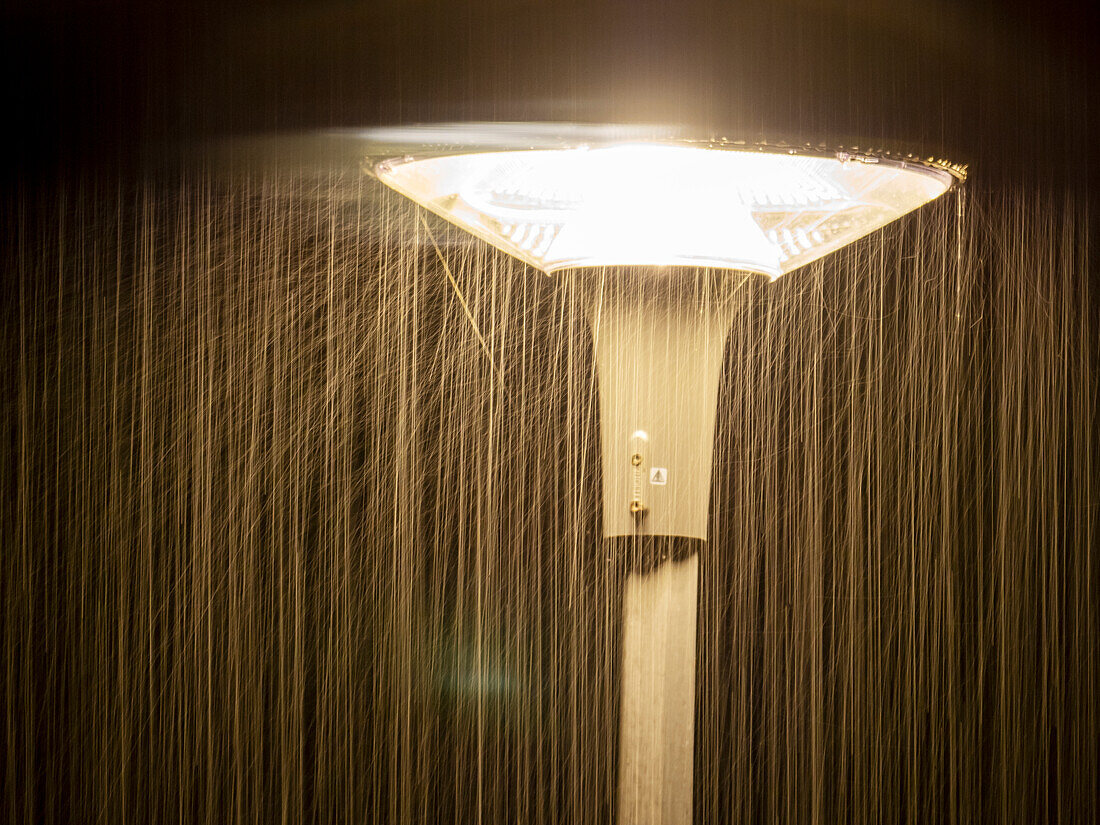 Heavy rain falling on a street lamp