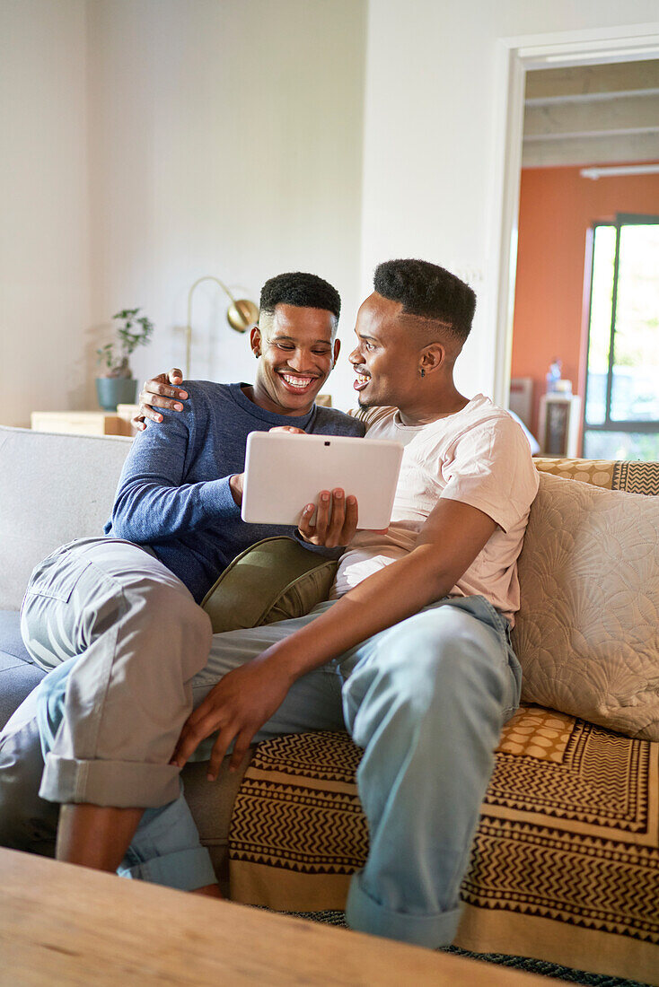 Happy young gay male couple using digital tablet