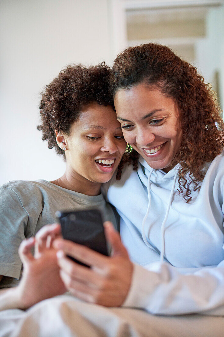 Happy lesbian couple using smart phone
