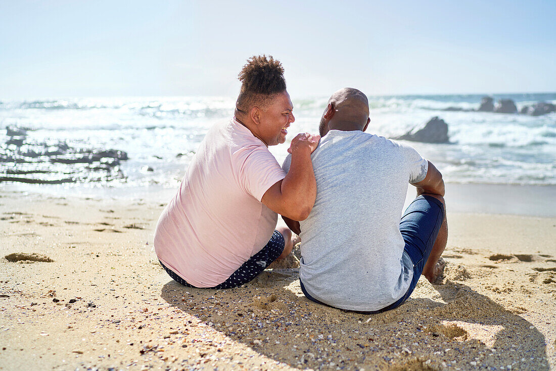 Gay male couple laughing on beach