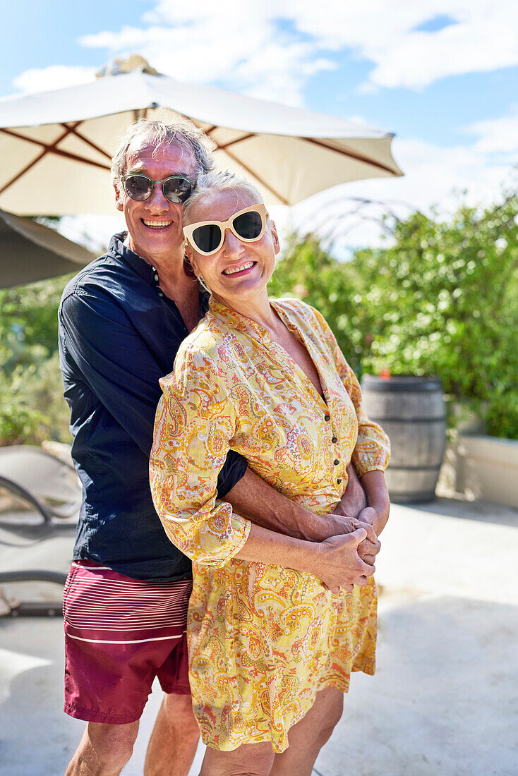 Senior couple hugging on sunny patio