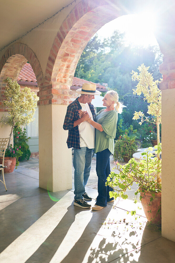 Senior couple dancing on sunny villa patio