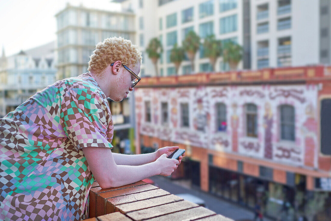 Young man using smart phone on urban balcony