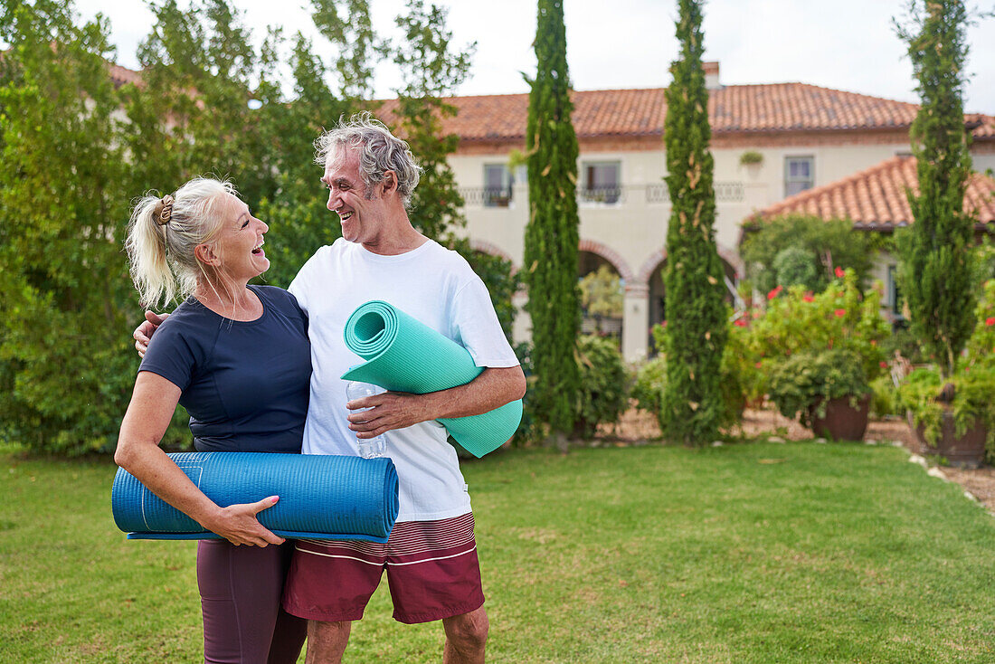 Senior couple with yoga mats in villa garden
