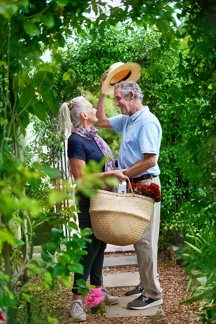 Senior couple with flowers under trellis in summer garden