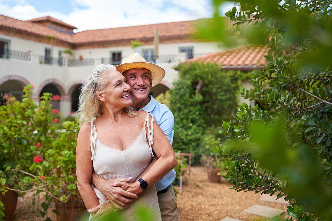 Senior couple hugging in garden outside summer villa