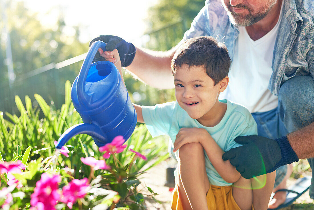 Boy with Down syndrome watering flowers with father
