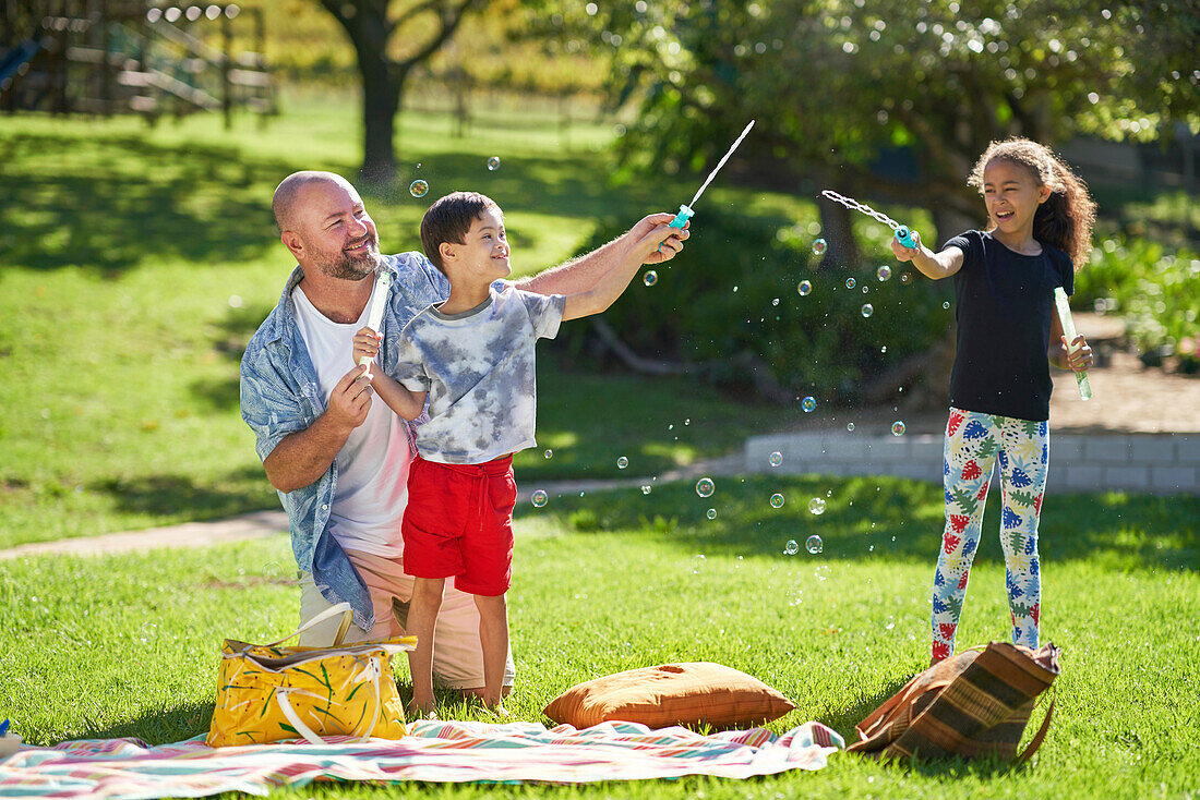 Family playing with bubbles in sunny park