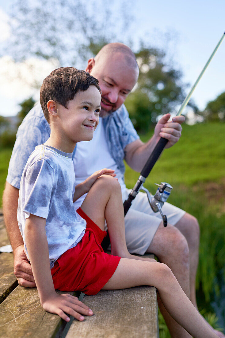 Father and son with Down syndrome fishing on dock