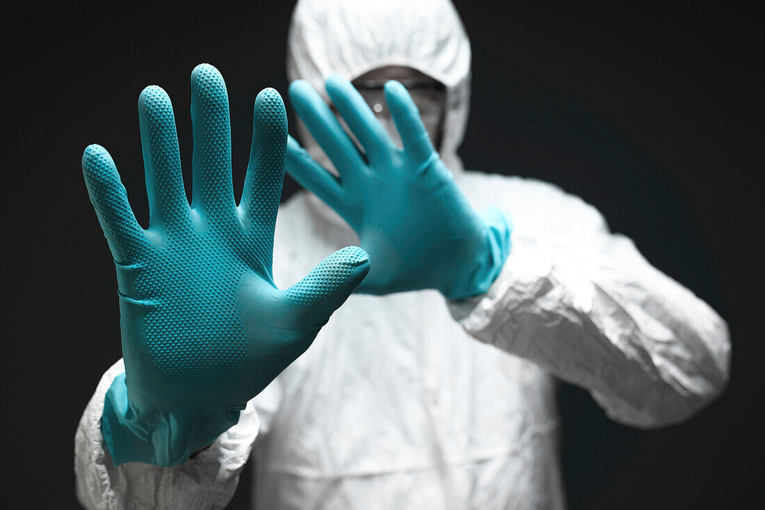 Medical professional in coverall gesturing stop