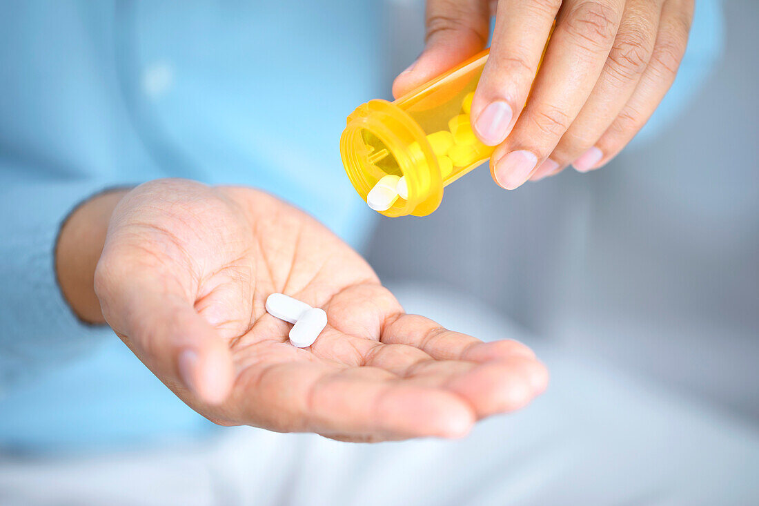 Man pouring pills into hand
