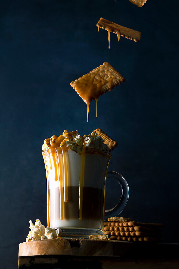 Floating caramel biscuits fall into coffee latte with popcorn and caramel