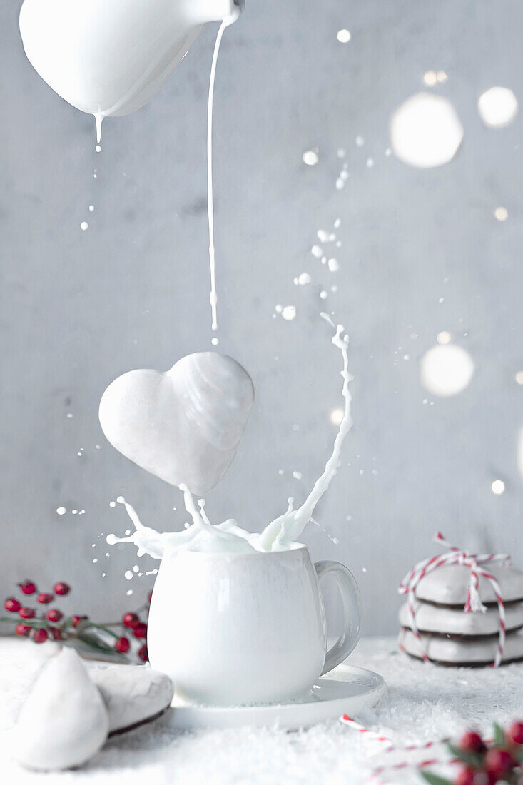 Glazed gingerbread heart falls into cup of milk