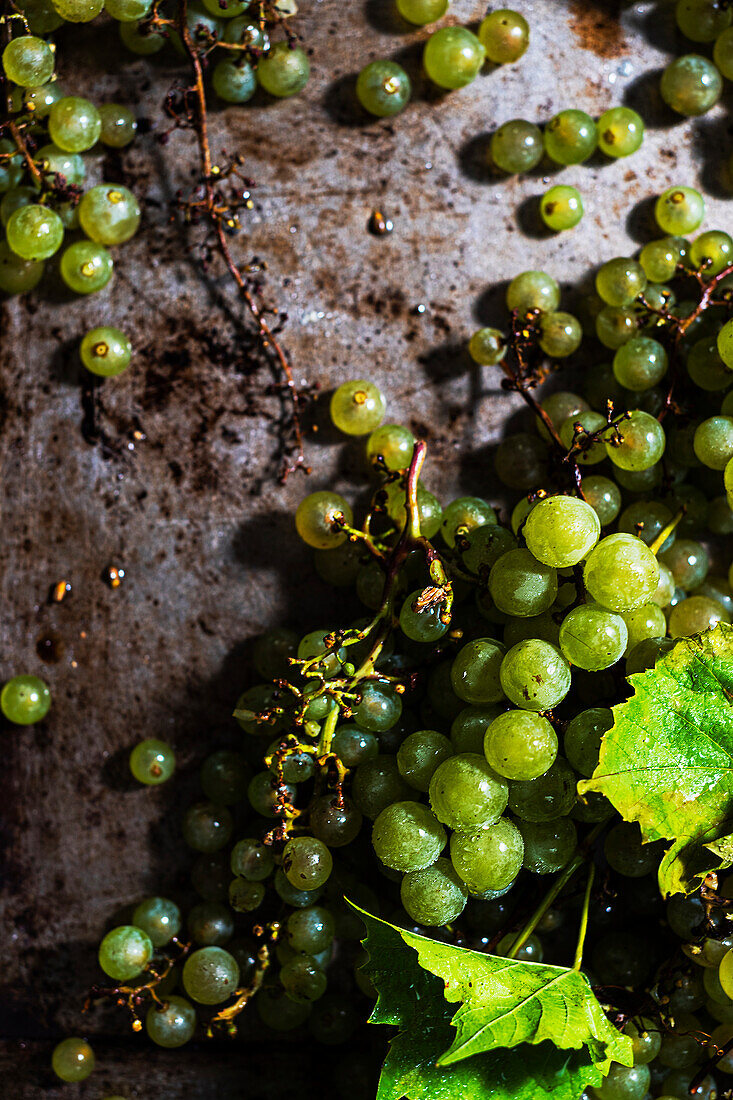 Fresh green grapes with leaves on a rusty background