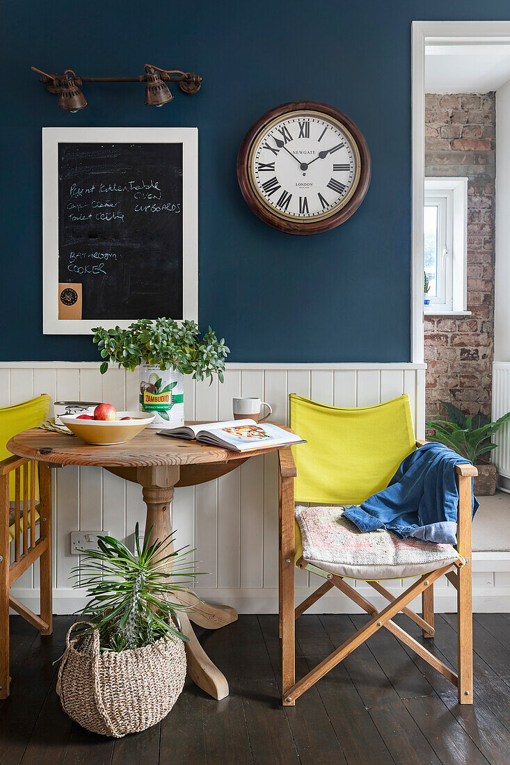 Dining area with wooden table and yellow director's chairs in front of dark blue wall