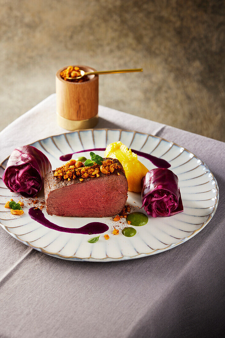 Saddle of venison in purple curry sauce with red cabbage rolls and pumpkin puree