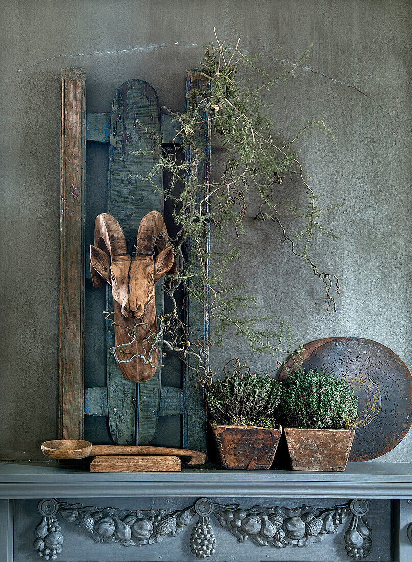 Decorative goat head sculpture and plants on a mantelpiece