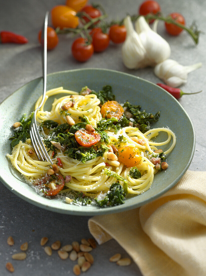 Spaghetti with kale, roasted pine nuts, tomatoes and Parmesan cheese