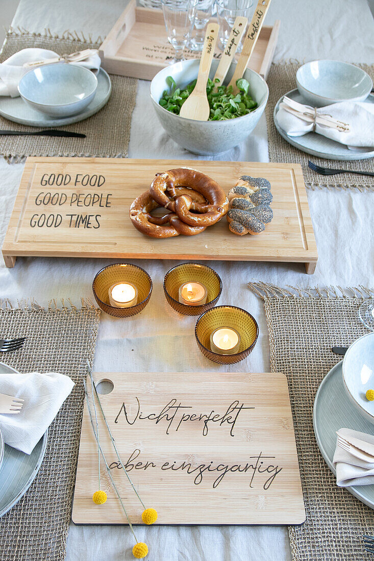 Table setting with pretzels, cold cuts and candlelights on wooden boards