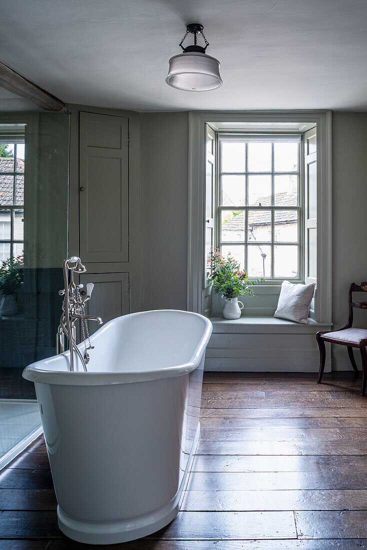 Freestanding vintage bathtub in the bathroom with window bench