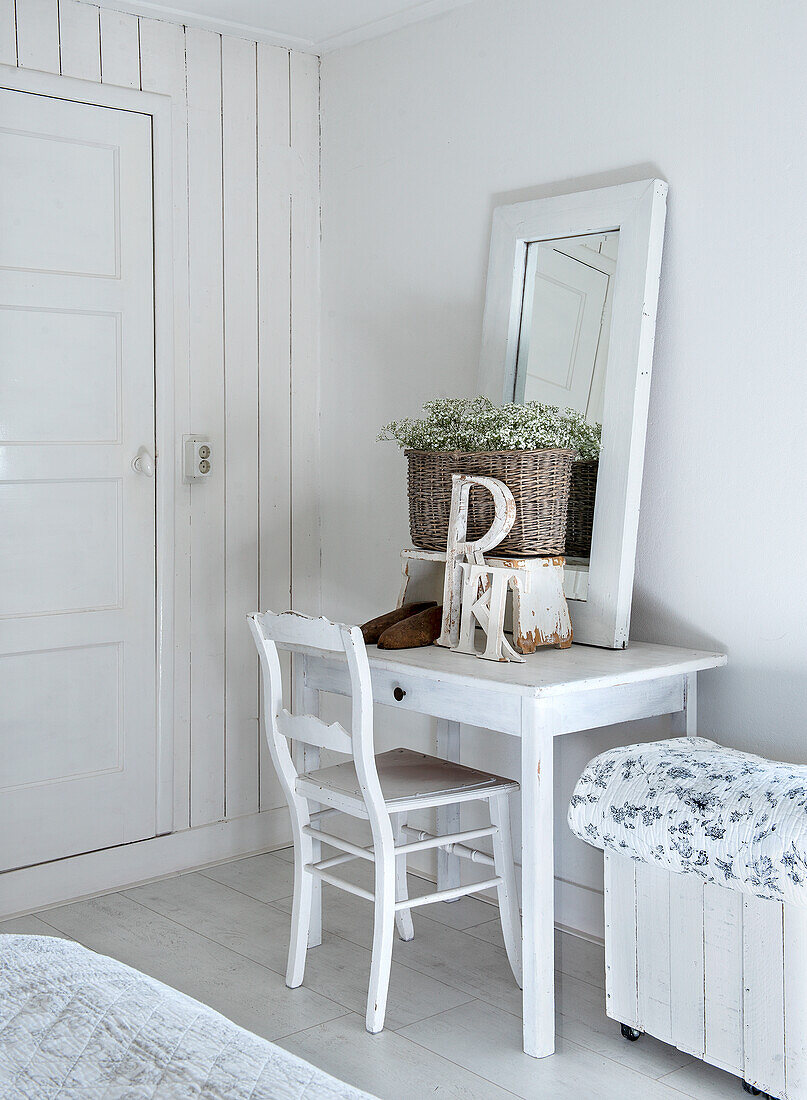 Frisiertisch mit Spiegel und Blumenkorb im weißen Schlafzimmer