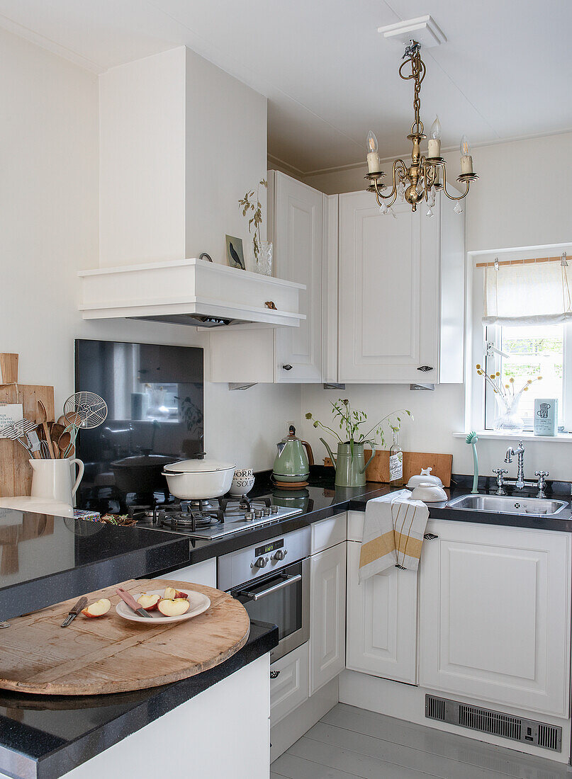 Kitchen corner with white cabinets, black counters and chandelier