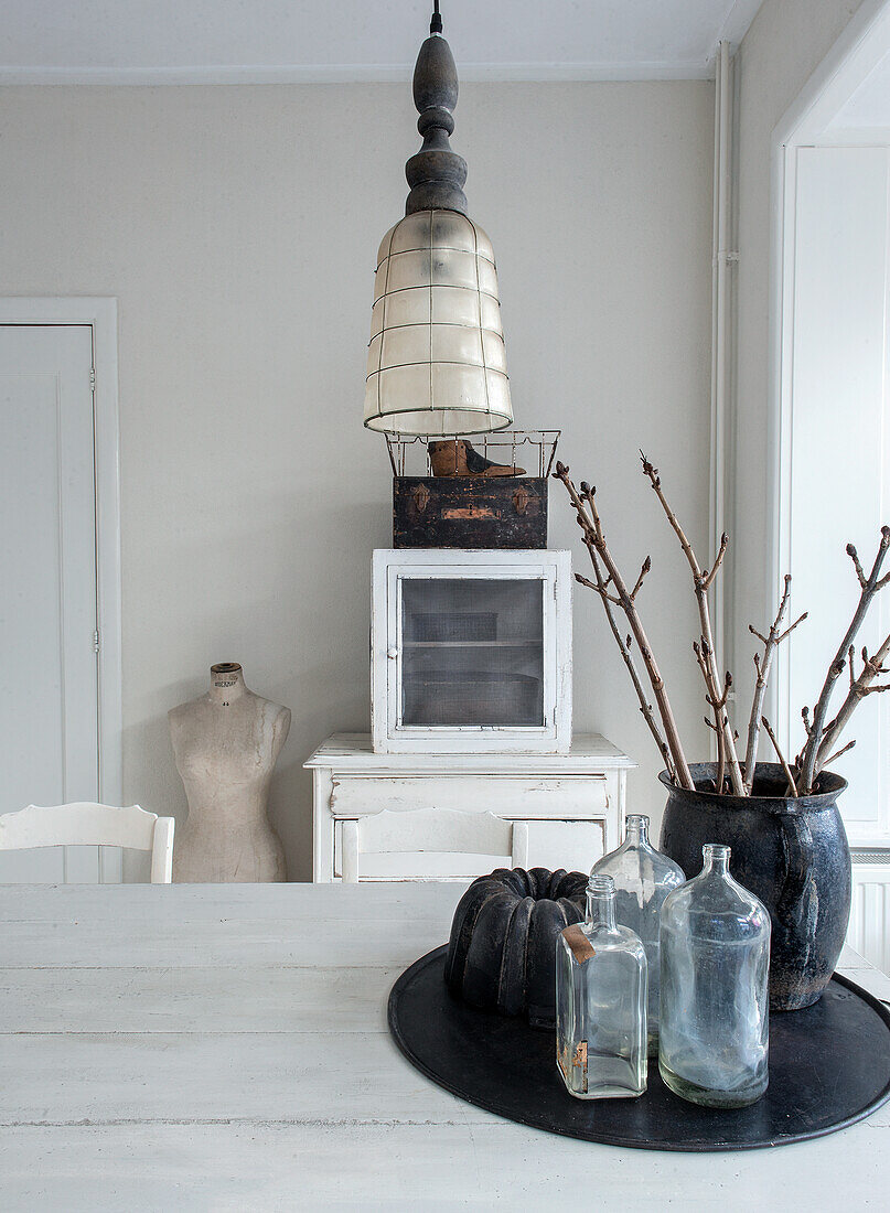 Glass bottles and ceramic vase with branches on a white table