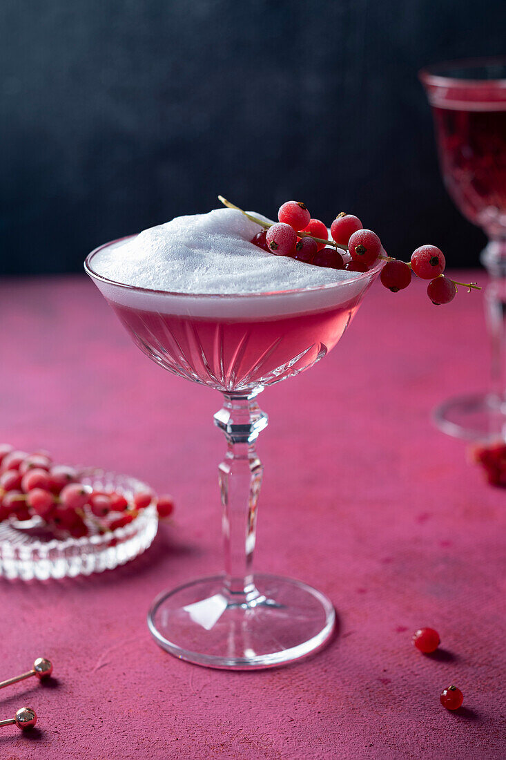 Pink Lady Cocktail mit gefrorenen, roten Johannisbeeren