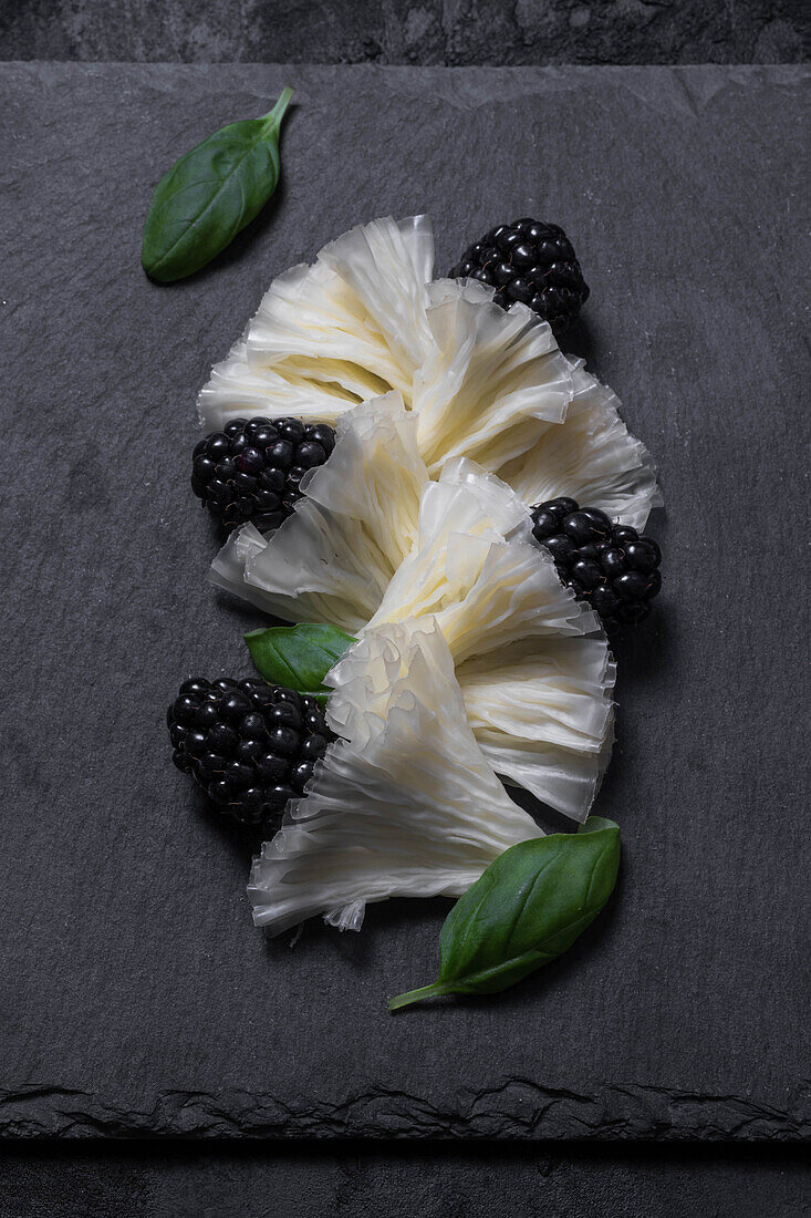 Tete de moine, blackberries and basil on a black serving board