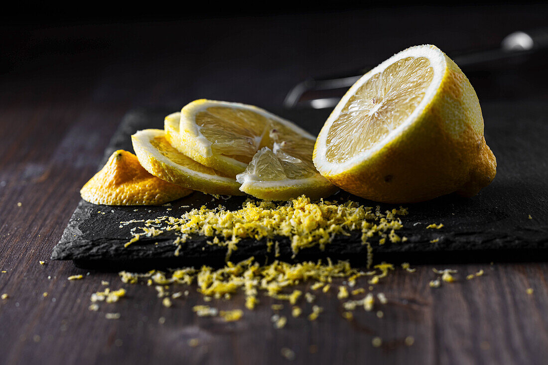 Sliced lemon, grated lemon peel on a dark background