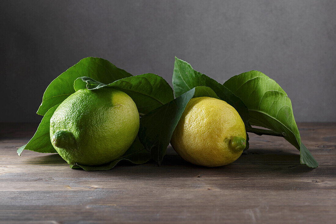 Lemons with leaves on wooden surface