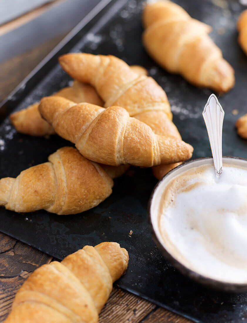 Croissants on baking tray and latte