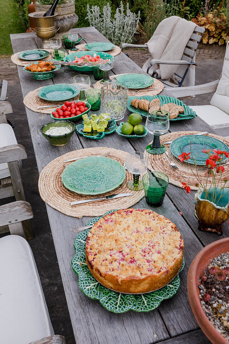 Variously laid table in the garden with green ceramic crockery