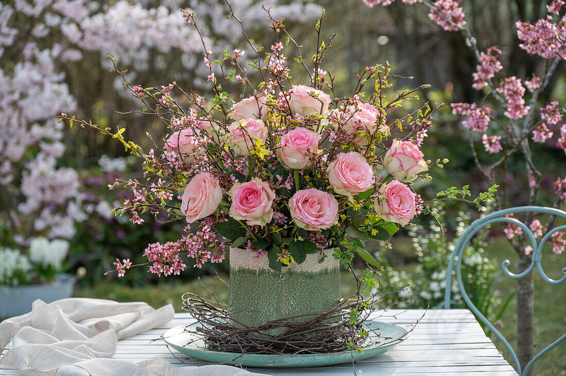 Bouquet of forsythia branches and roses, and twigs as table decoration