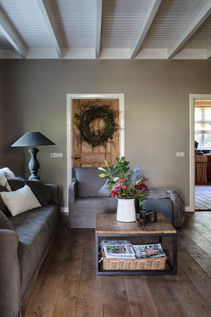 Dark grey furnished living room with white wooden beamed ceiling and wooden floorboards