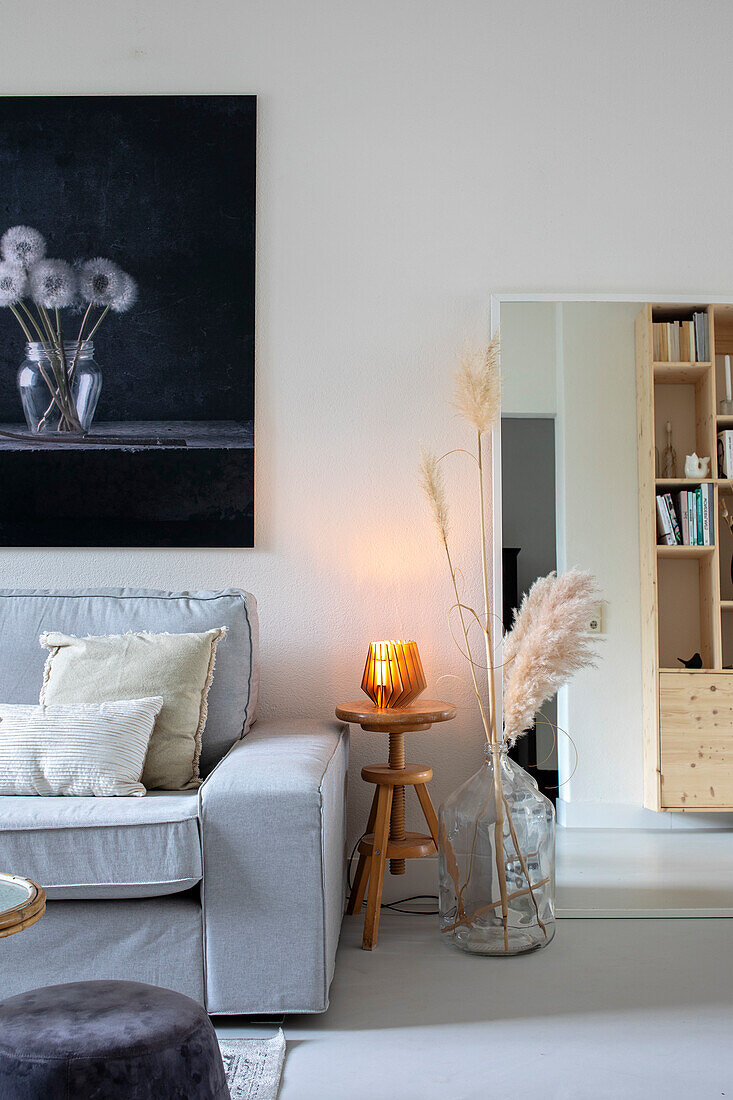 Sitting area with grey sofa, wooden side table and large black and white art on the wall