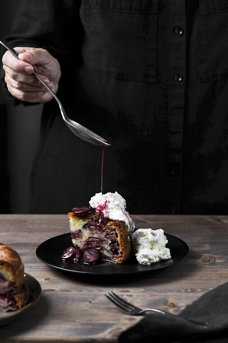 Sauce drizzling on plum cake with compote and cream