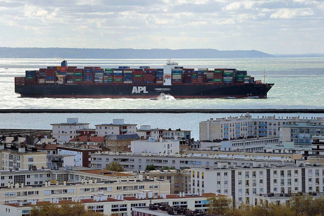 France,Seine Maritime,Le Havre,a container ship leaves the commercial port and seems to follow the buildings